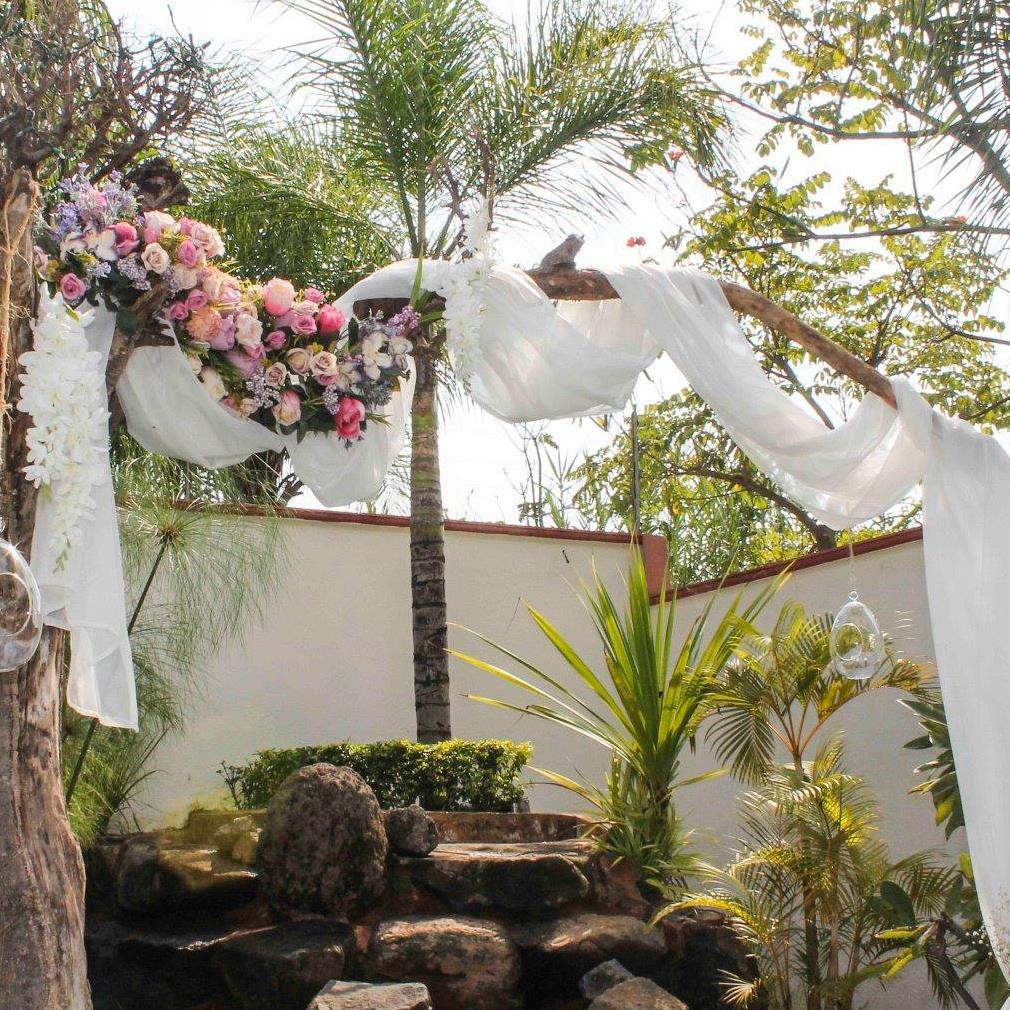 Altar floral exterior con telas blancas y flores rosas